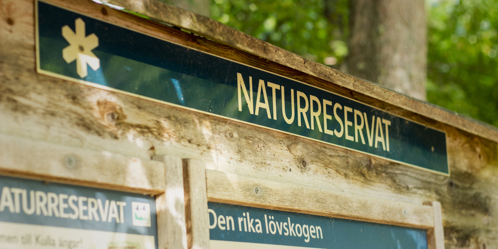 Skylt i skogen över naturreservat